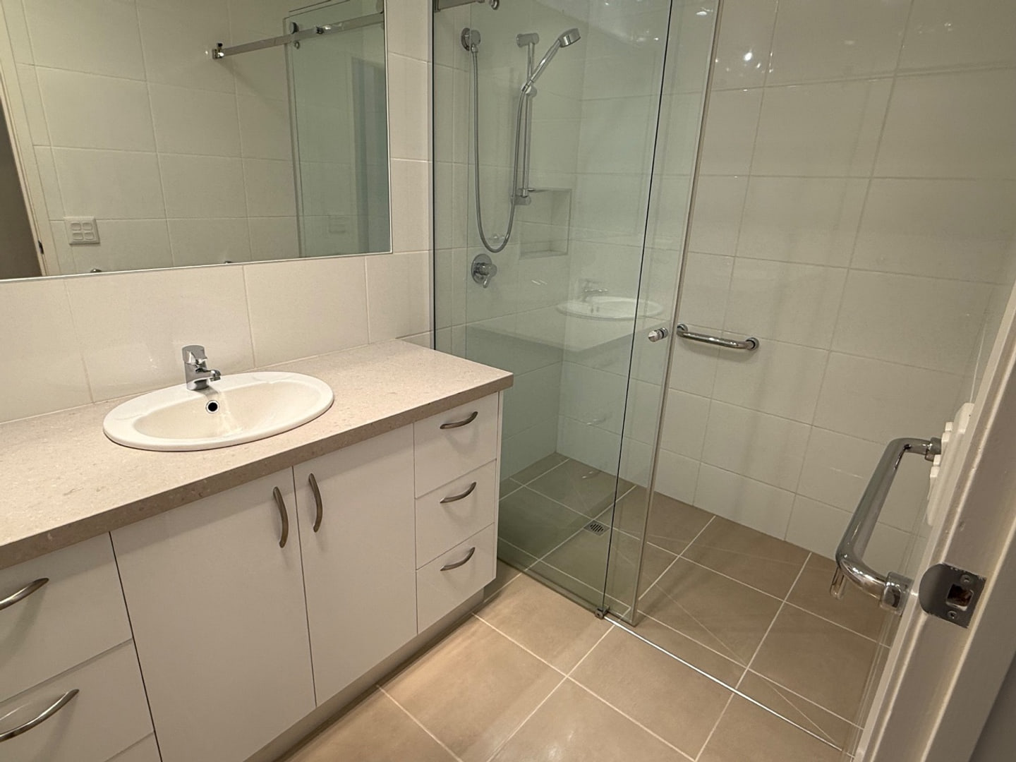 Clean bathroom fixtures, glass and tiled surfaces prepared for handover