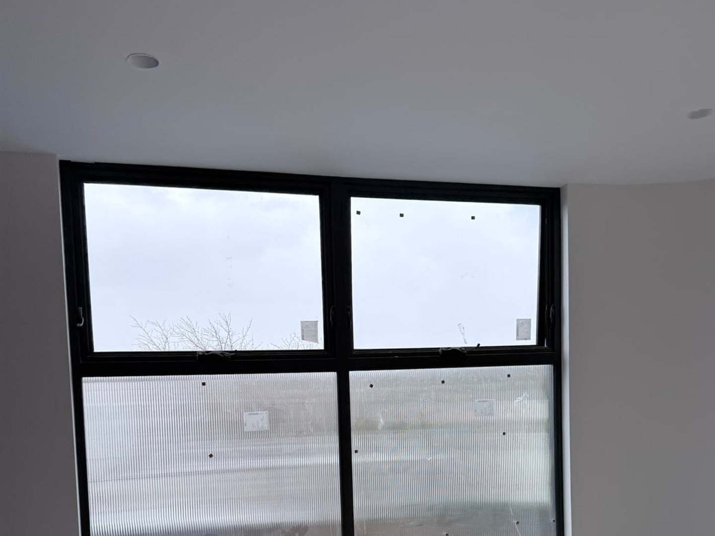 Protected floor, glazing labels and construction residue before handover cleaning